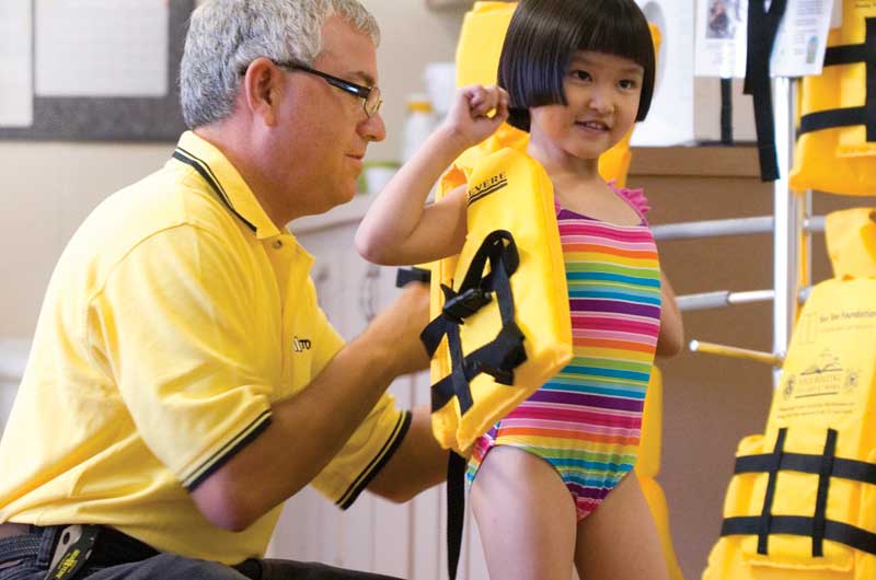 Captain Kerry Kline fitting a child for a life jacket for boating safety.