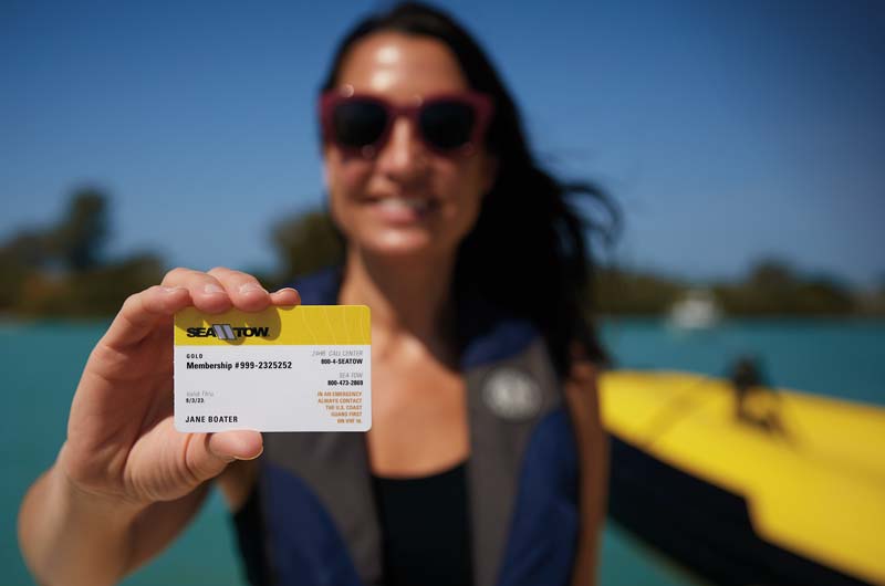 woman holding sea tow gold card to receive exclusive marine discounts.
